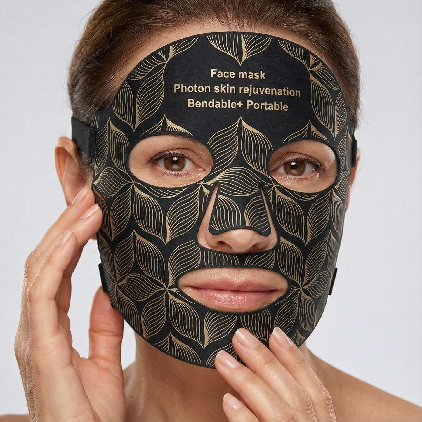 Woman wearing a black face mask with gold leaf patterns on a white background
